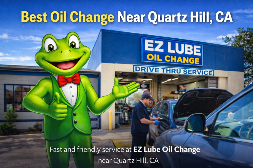 EZ D’Frog mascot stands in front of EZ Lube Oil Change in Lancaster, California, near Quartz Hill, as technicians provide fast, friendly, drive-thru oil change service to a vehicle.